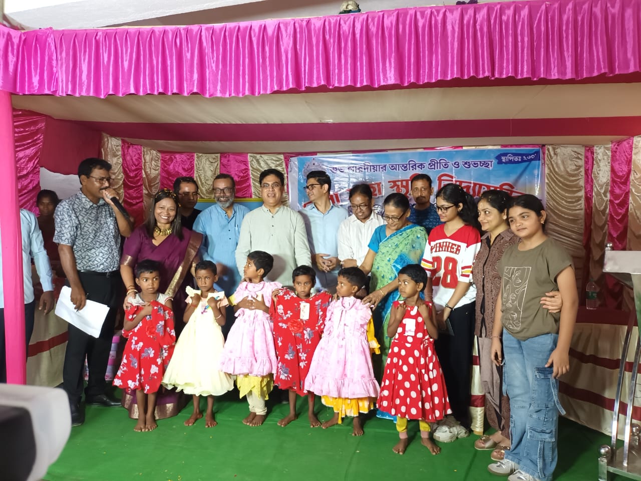 Volunteers and well-wishers standing with children holding their new dresses